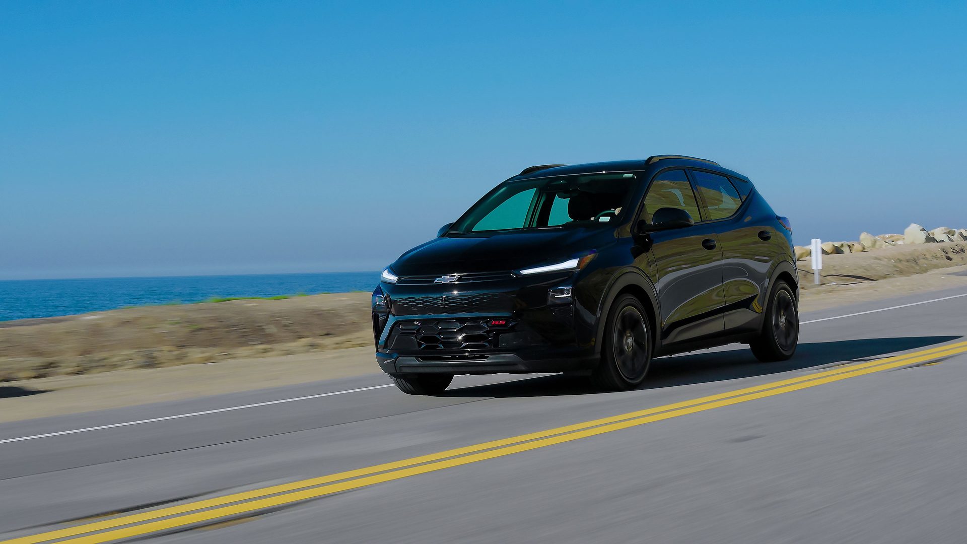 2027 Chevrolet Bolt RS in Mosaic Black Metallic on a coastal road
